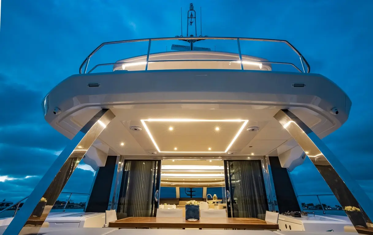 Luxury yacht interior at dusk, highlighting modern design with bright overhead lights and sleek, stylish finishes.